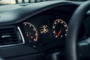 Detailed view of a car's dashboard featuring illuminated gauges and speedometer.