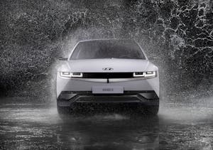 Dynamic front view of a Hyundai Ioniq 5 splashing through rain, captured in black and white.