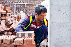 Focused worker laying bricks at construction site in Hải Phòng.
