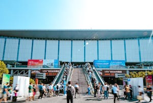 People entering Shanghai exhibition center via outdoor escalator during daytime.